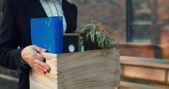 Side Close Up View of Female Office Worker in Formal Wear Carrying Box with Her Belongings While alt