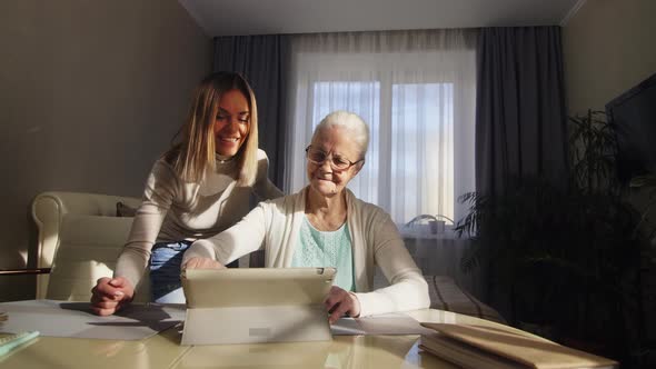 Senior Woman Learning Tablet with Help of Adult Granddaughter