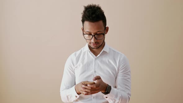 Man Texting on Smartphone Than Smiling and Looking to Camera