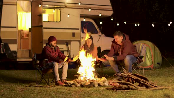 Friends Warming Up Their Hands During a Cold Night at Camp Fire alt