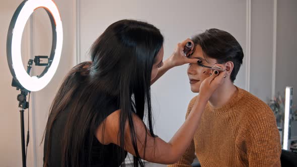 Make Up Artist Doing a Brown Bold Lips Look on Her Male Model - Applying Mascara alt