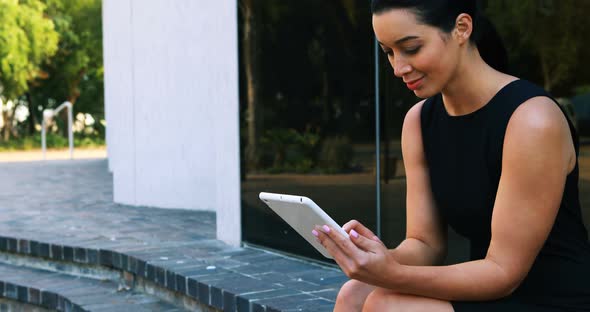 Businesswoman sitting on steps and using digital tablet 4k alt