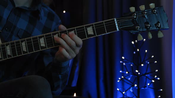 Professional guitarist is strumming acoustic guitar in dark cozy room. alt