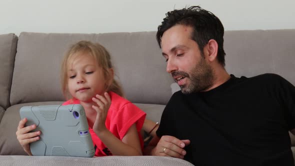 Father and Daughter Connected with Tablet Sitting on Couch