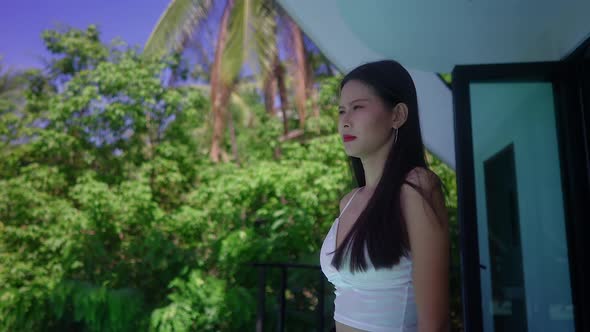 Cute Asian Girl in Front Of A Luxurious Villa Looking Away Surrounded By Nature