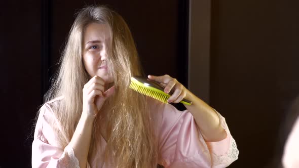 Unhappy Woman with Dry Brittle Hair Checking Her Tangled Hair in Mirror alt