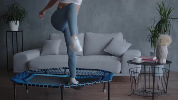 Energetic Young Woman in Sportswear Jumps on a Mini Trampoline Enjoys