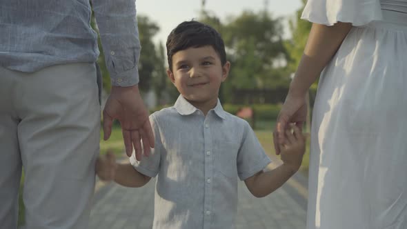 Portrait Cute Middle Eastern Boy Holding Hands Parents Turning To Camera alt