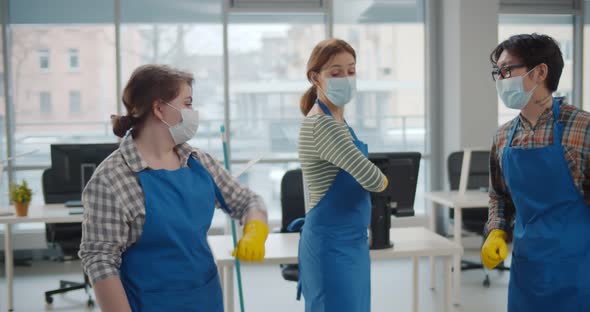 Professional Office Cleaning Janitors in Safety Mask Bumping Elbows at Workplace alt