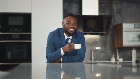 African Smiling Businessman Enjoying Morning Coffee at His Kitchen alt