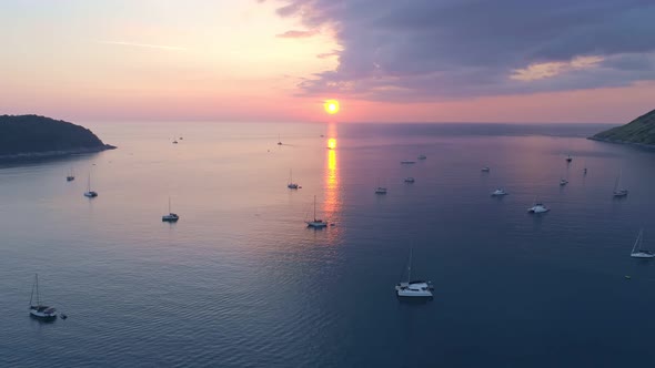Colorful sunset above the sea surface with sail boats. Aerial view drone fly over Phuket sea alt