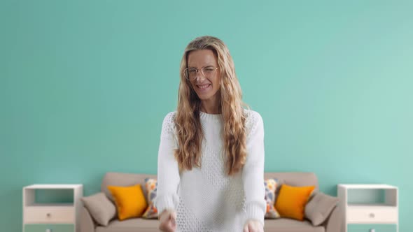 Smiling Woman Is Showing Thumbs Up Isolated on a Blue Room Background alt