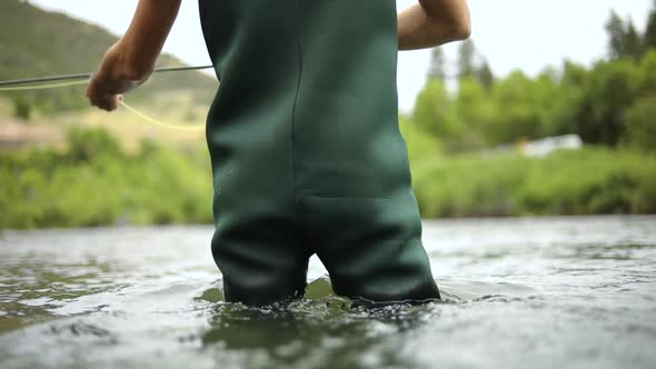 Shot of a male fisherman wearing waders while Fly Fishing. He is standing in the middle of the Provo alt