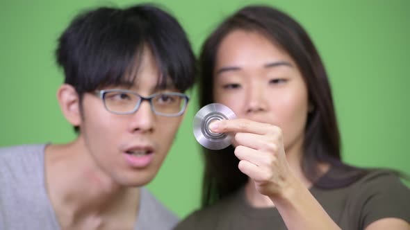 Young Asian Couple Playing with Fidget Spinner Together