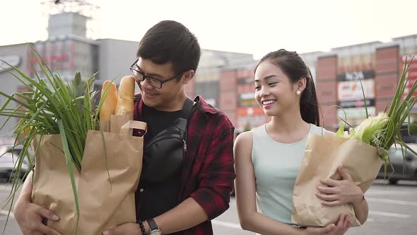 Smiling Vietnamese Couple Going from the Supermarket with Bags Full of Various Food alt