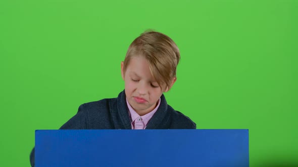 Teenager Peeks Out From Behind the Boards and Shows Dislike on a Green Screen alt