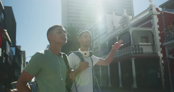 Two mixed race male friends standing, trying to catch cab in the street alt