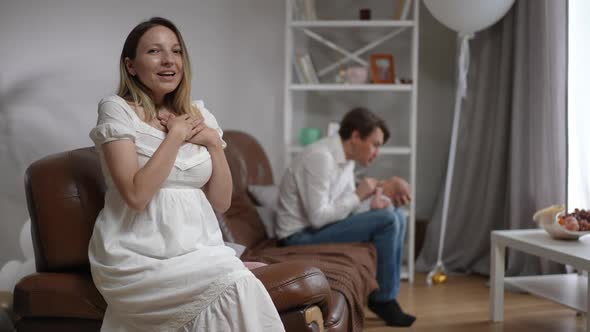 Loving Happy Caucasian Woman Admiring Man and Newborn Infant Sitting at Background Looking at Camera alt