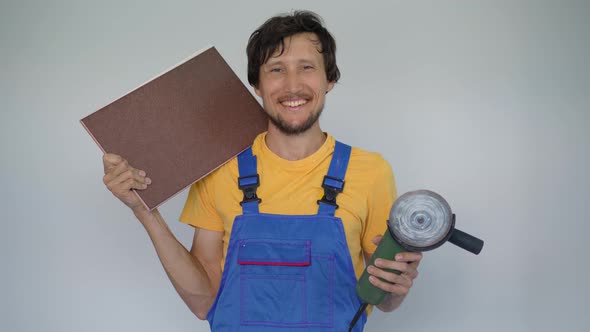 A Man Professional Tile Installer Holds a Tile and an Angle Grinder His Arms alt