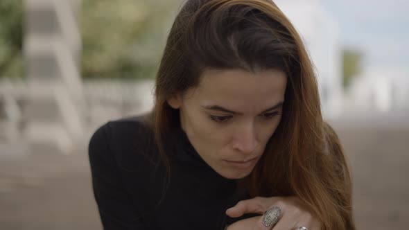 Closeup of Young Devastated Darkhaired Woman Looking Down and Shaking alt