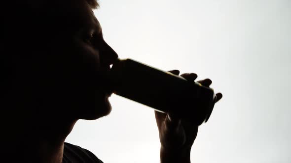 The Silhouette of Male head drinking from a aluminum can