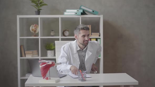 Younger Doctor Greeting His Older Colleague, Who Entering the Office with X-ray in Hands in Modern alt