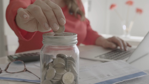 Mujer gestiona cuentas y ahorra monedas de dos euros en un hucha alt