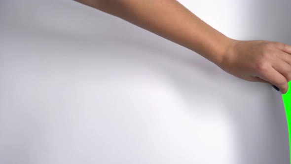 Female Hand Flips a White Sheet of Paper on a Green Screen. alt