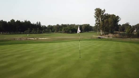 Flying through flag on golf field in close up drone shot alt