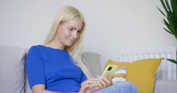 Woman sitting on couch using smartphone