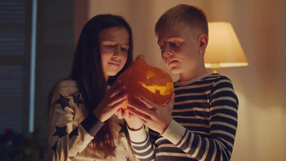 Boy and Girl Playing with Carved Pumpkin at Home on Halloween alt