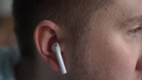 Man Inserts a Wireless Headset Into His Ears Listens to Music Shakes His Head