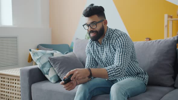 Happy Middle Eastern Man Relaxing in House Playing Video Game Holding Control alt