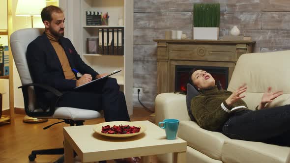 Psychotherapist Taking Notes While Unhappy Woman alt