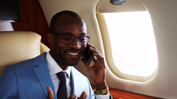 Successful entrepreneur talking on the phone on his private jet alt