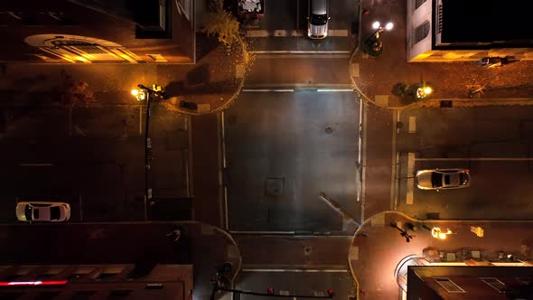 Top down rising aerial of car in intersection. One way streets at night. Street light and vehicle he alt