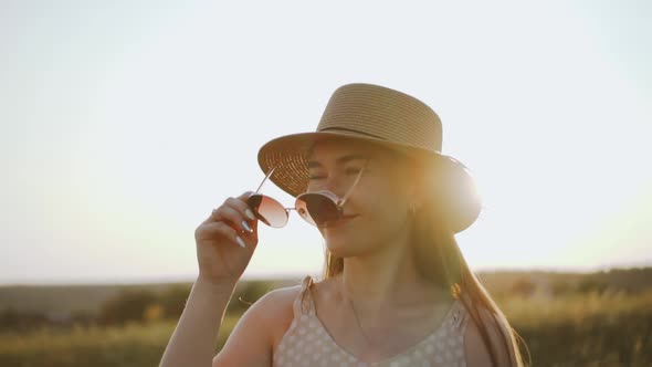 Woman in Hat Wearing Sunglasses and Smiling Rural Landscape