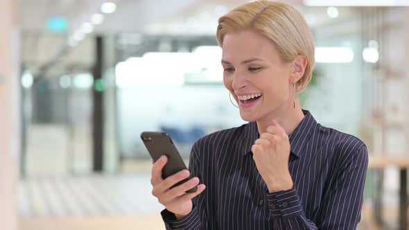 Excited Businesswoman Celebrating Success on Smartphone  alt