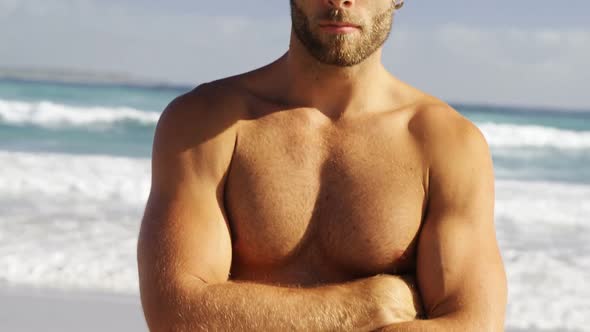 Portrait of male surfer standing with arms crossed in the beach alt
