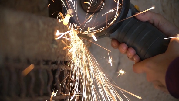 Closeup of worker using a grinder cuts metal in a workshop