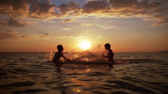 Silhouettes of Two Happy Boys 1012 Playing and Splashing Water While Swimming in Sea During alt