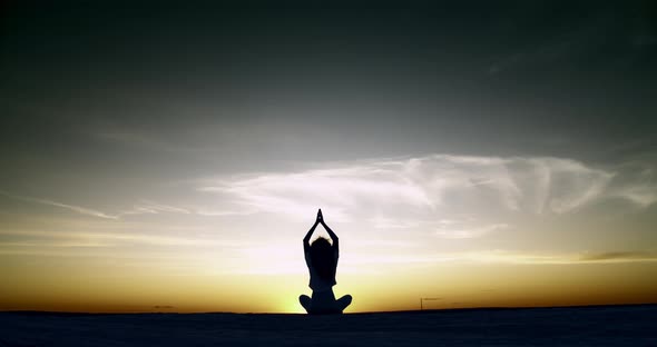 Silhouette of a Girl Doing Yoga Sitting at Sunset alt