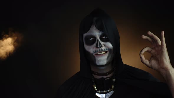 Scary, Creepy Man in Skeleton Halloween Costume Looking at Camera with Smile, Showing Ok Gesture alt