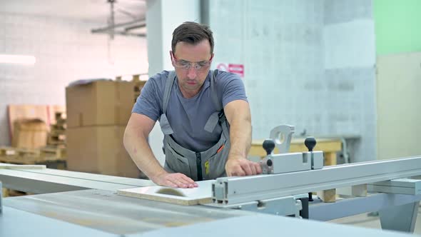 young man works on a circular saw in a furniture workshop alt