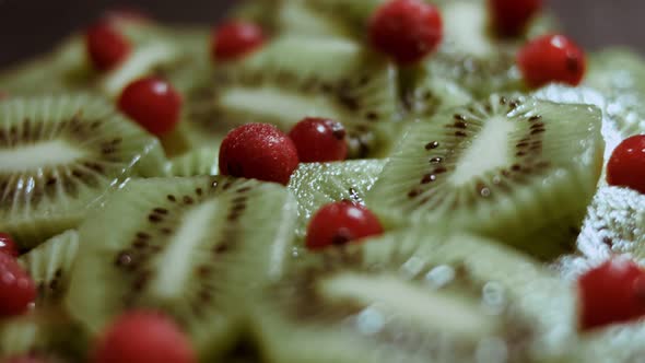 Juicy Fresh Kiwi Slices and Frozen Red Currant Arranged in a Shape of Christmas Tree on a Black alt