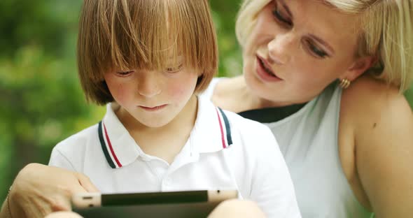 Down Syndrome Boy Scrolling Tablet with Mother