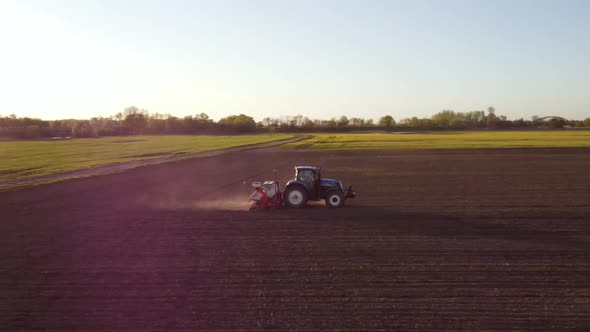 Tractor Working in Field at Sunset alt