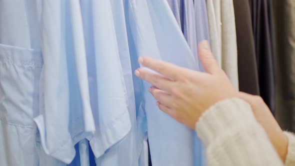 Female Hands Closeup Sorting Out Men's Shirts on a Hanger in Blue alt