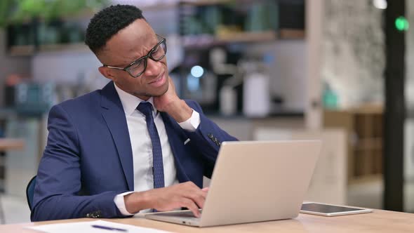 Tired African Businessman with Laptop Having Neck Pain in Office  alt