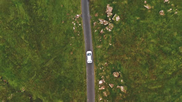 Aerial Top View of Generic Electric Car Driving on Country Road in Faroe Islands alt